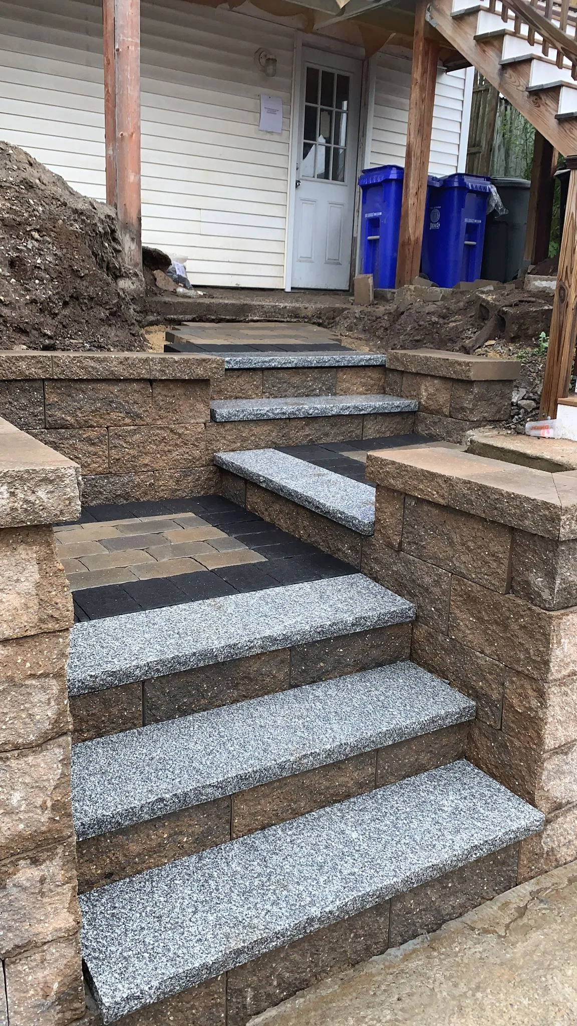 Granite tread steps between block walls with an inset paver landing at the top