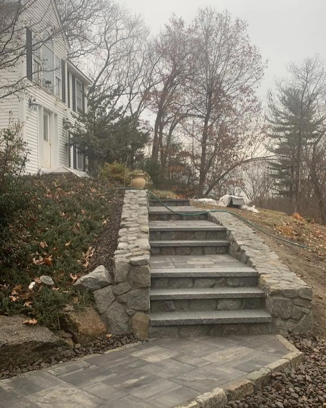 Granite steps flanked by natural fieldstone walls on a wooded slope