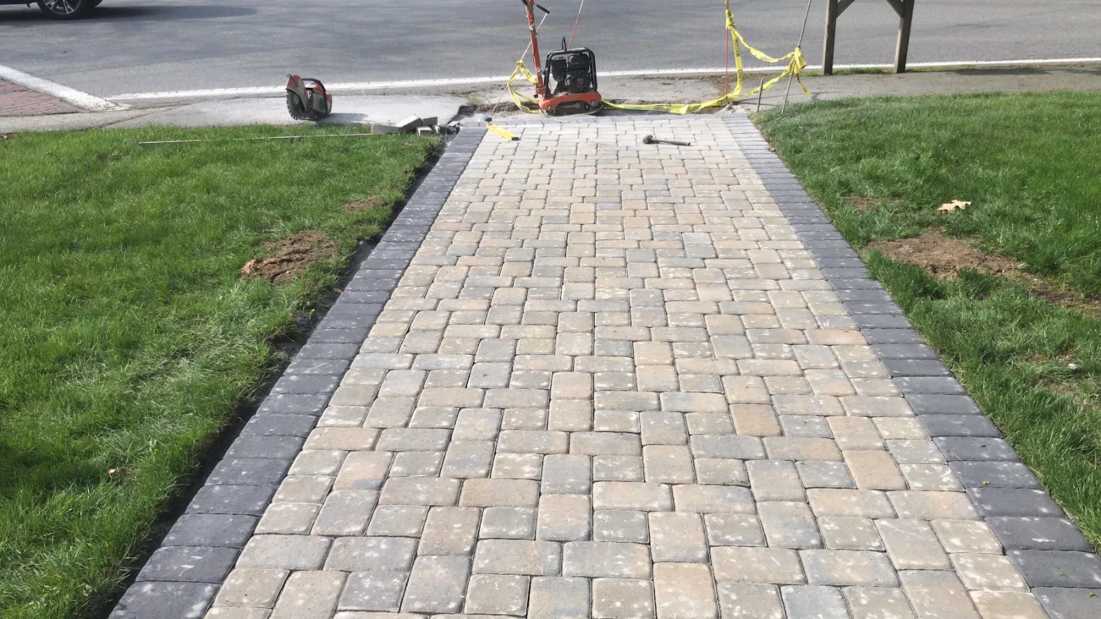 Paver walkway being compacted with a plate compactor during installation