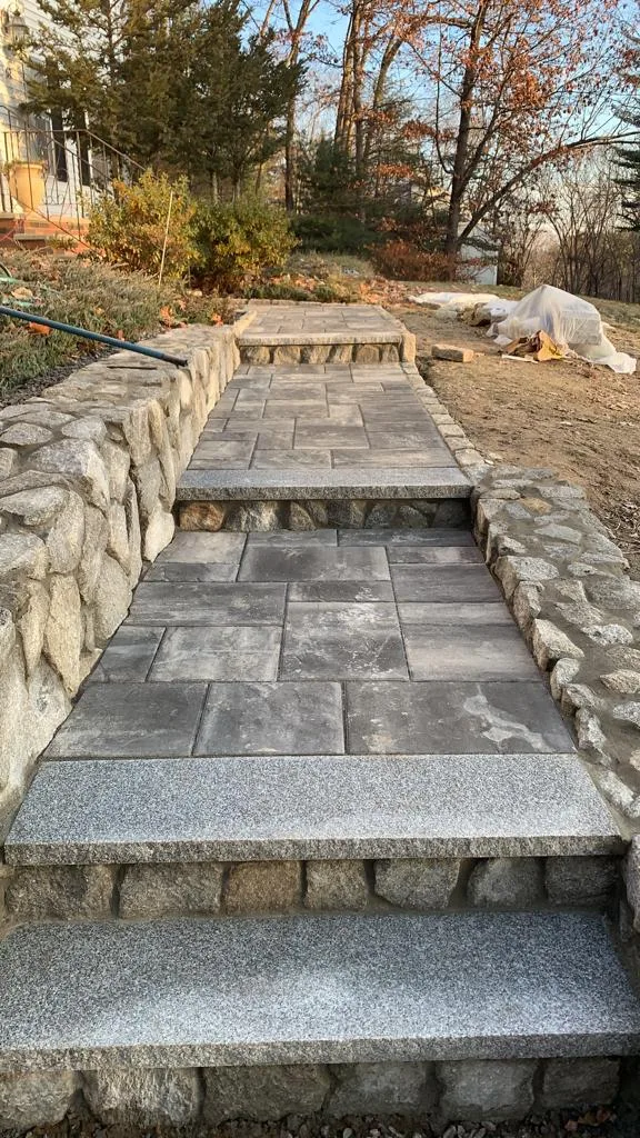 Paver walkway running between two natural fieldstone walls up to a landing