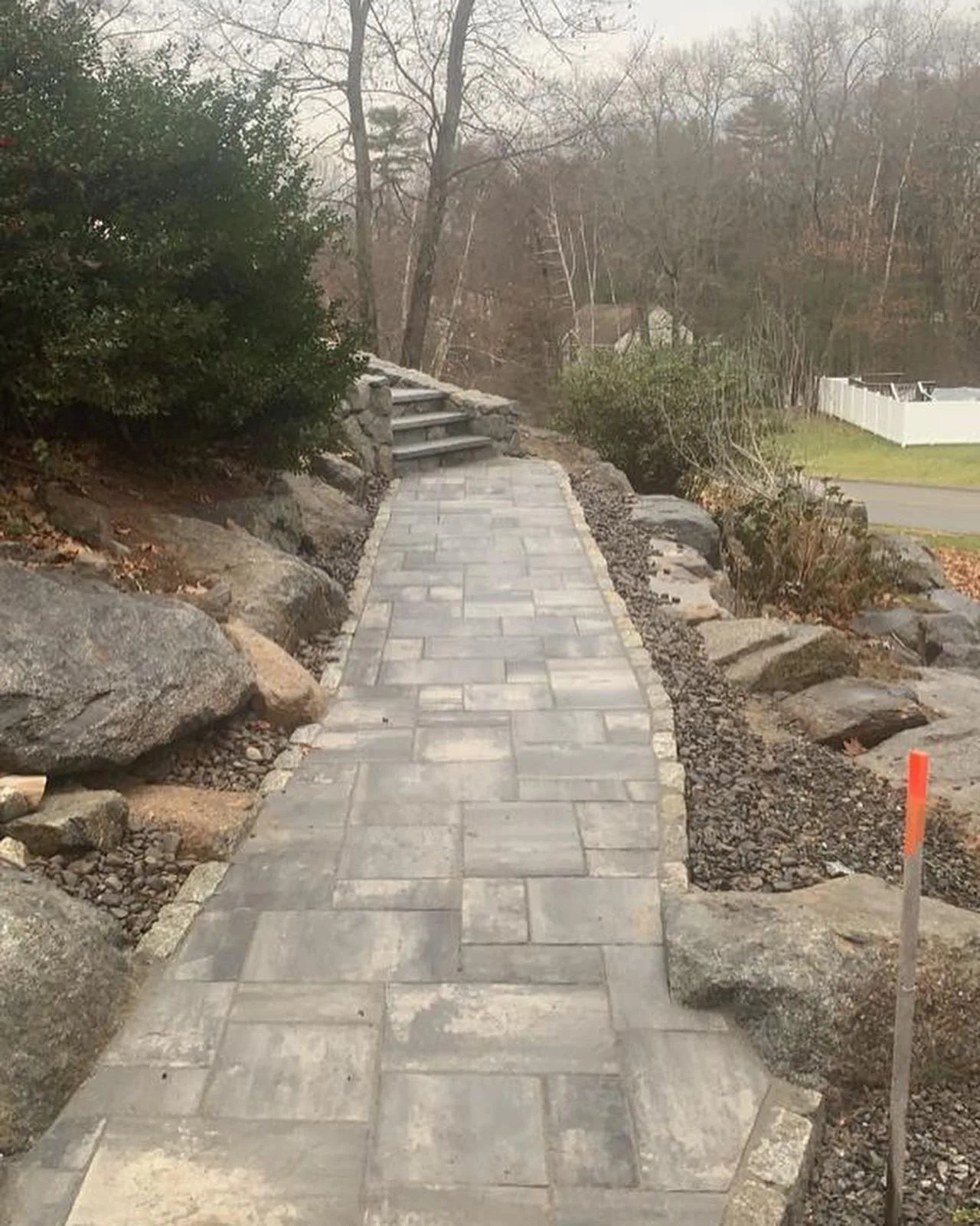 Paver walkway cut across a landscaped slope with stone edging on both sides