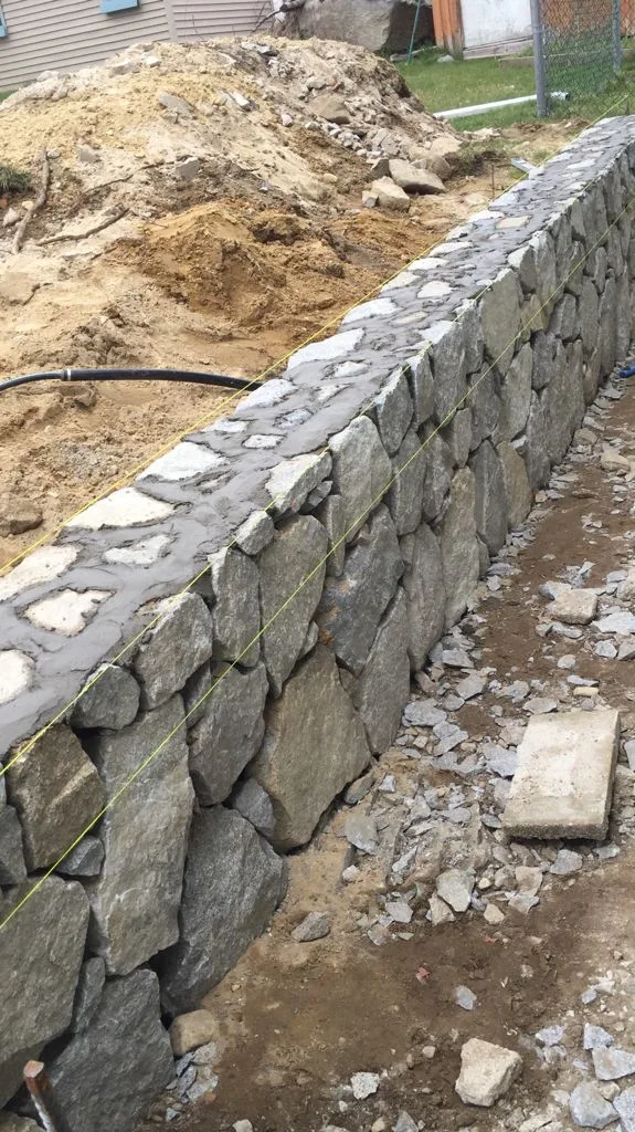 Fieldstone retaining wall under construction with drainage stone behind it