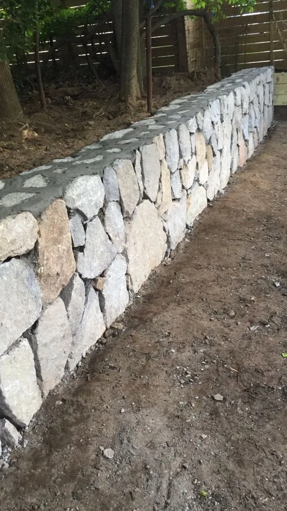 Close view of a natural fieldstone wall face showing hand-fitted stone